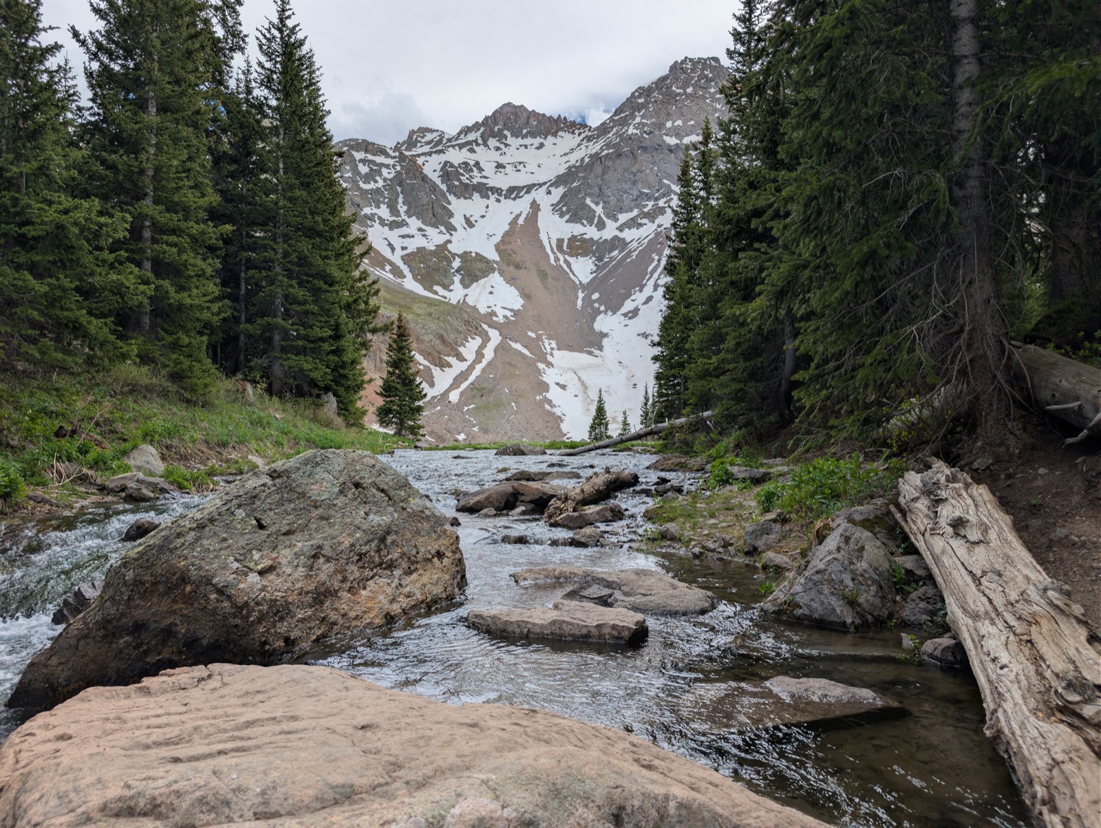 Alpine stream below snow-capped peaks